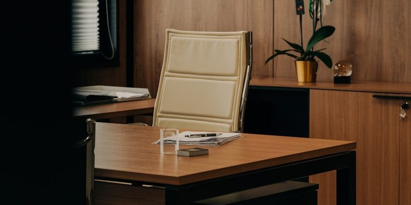a desk with a chair and a vase of flowers